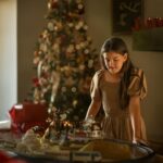 The girl looks at the train set toy.